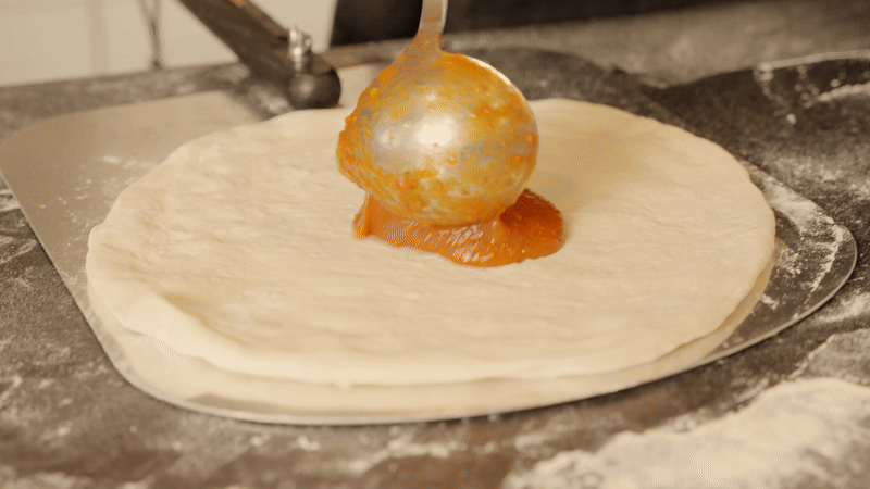 Spreading sauce on stretched dough