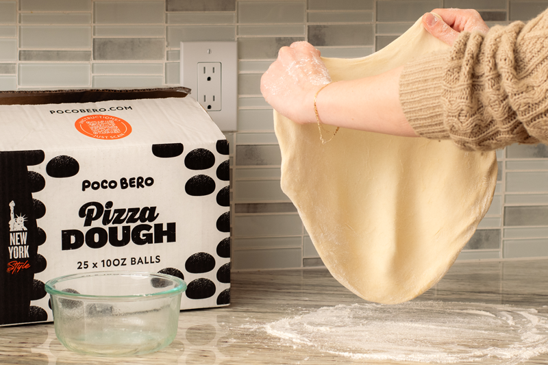 Poco Bero NY-style dough balls beside a baked pizza