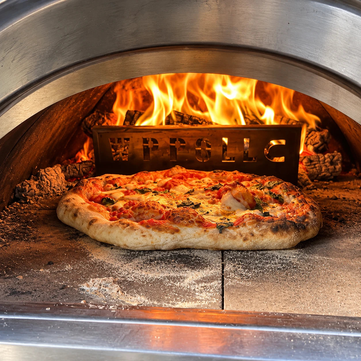 NY-style pizza baking in a wood-fired oven